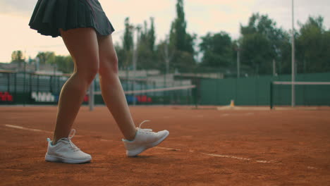 Slow-motion-close-up:-Young-Caucasian-teenager-female-tennis-player-serving-during-a-game-or-practice.-Tennis-Player-Serving-On-The-Clay-Court.